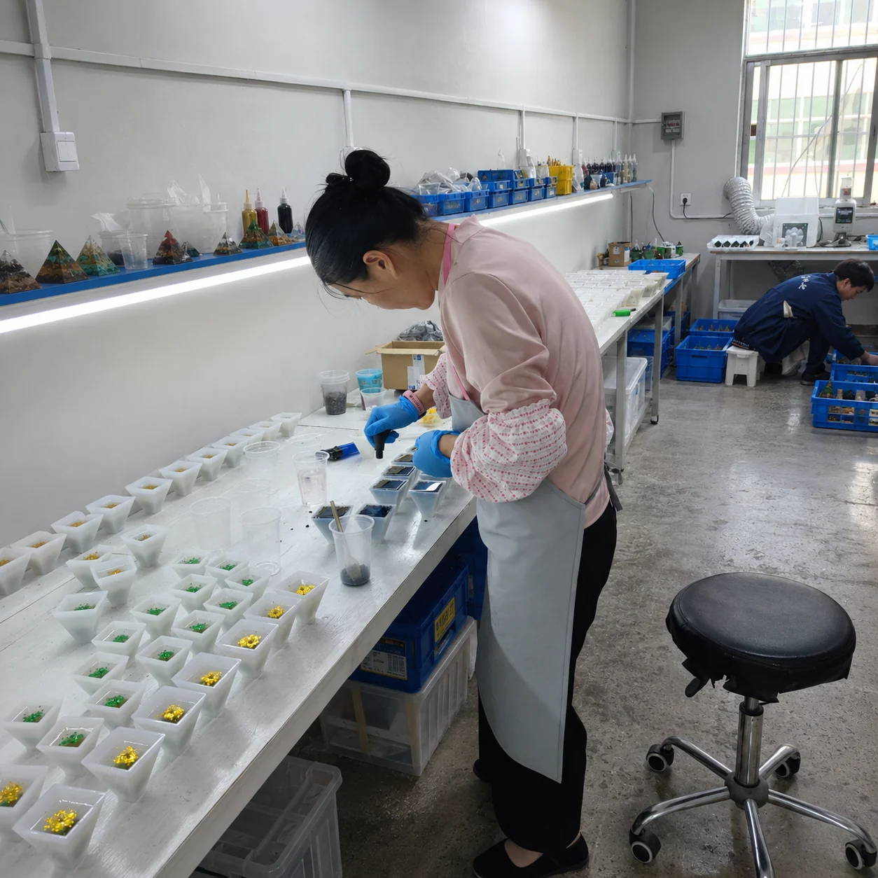 A worker making orgone pyramids with materials and moulds at a bench