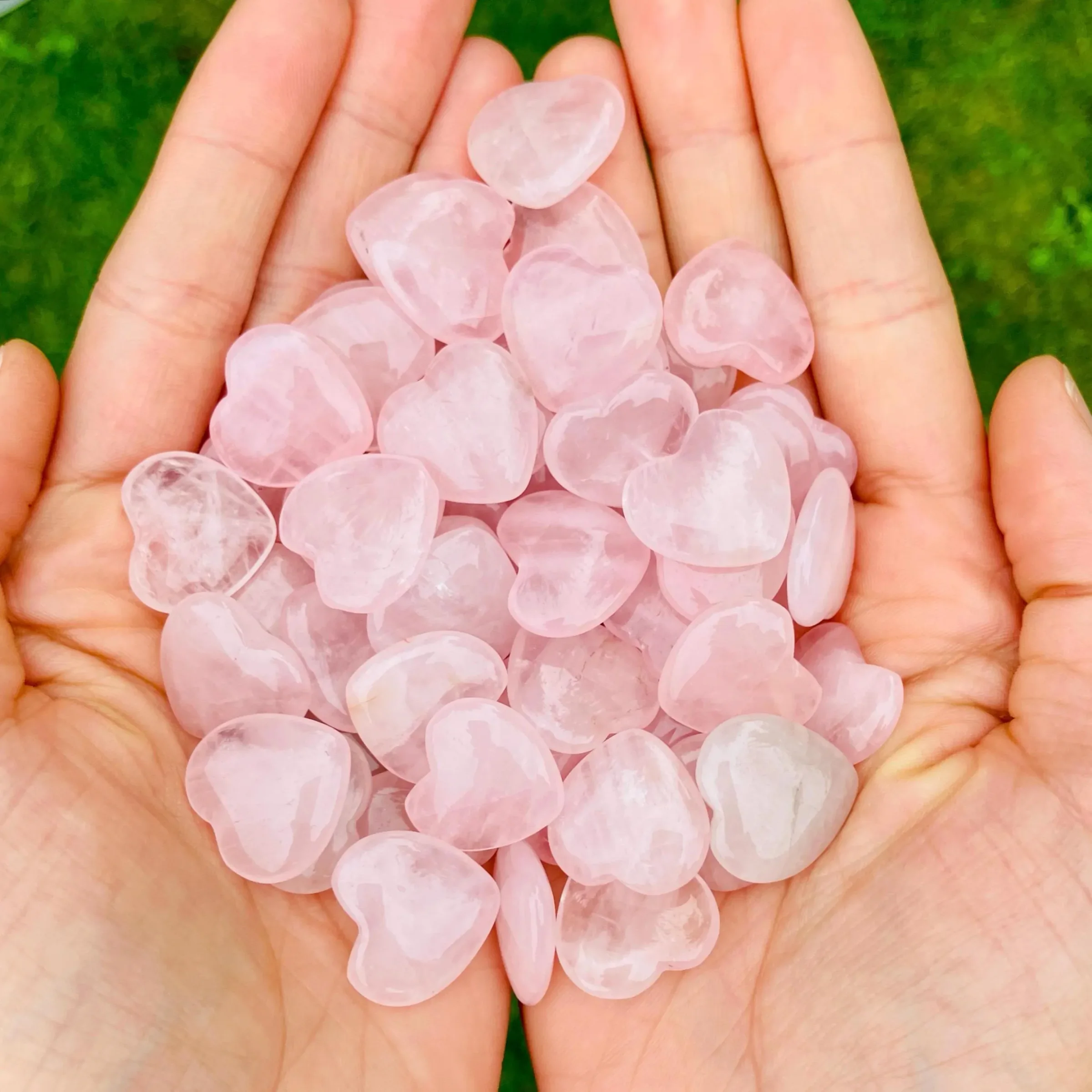 Small rose quartz hearts held in two hands