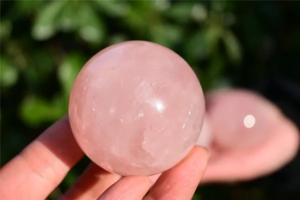 May include: A polished, spherical rose quartz crystal with a translucent, pale pink hue. The stone features natural internal inclusions and a smooth, reflectiv May include: A polished, spherical rose quartz crystal with a translucent, pale pink hue. The stone features natural internal inclusions and a smooth, reflective surface that catches the light, showcasing its soft, consistent pastel coloration.