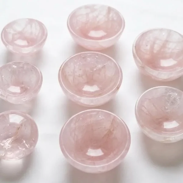 May include: Nine small, round, rose quartz bowls are arranged on a white surface. The bowls are a soft pink color and have a smooth, polished appearance. The b May include: Nine small, round, rose quartz bowls are arranged on a white surface. The bowls are a soft pink color and have a smooth, polished appearance. The bowls are of varying sizes and are ideal for holding small items or as decorative pieces.