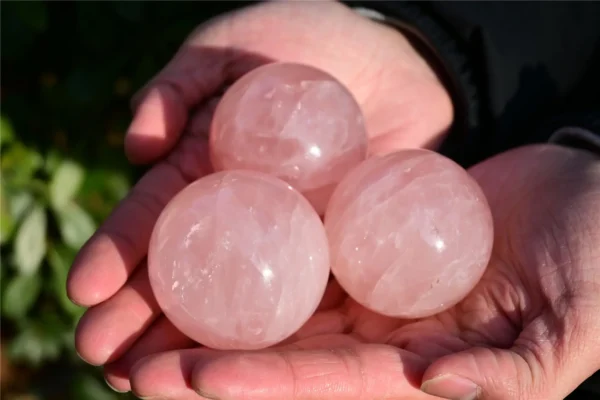 May include: Three polished rose quartz spheres with a translucent, pale pink appearance. Each stone features natural internal veining and a smooth, rounded sur May include: Three polished rose quartz spheres with a translucent, pale pink appearance. Each stone features natural internal veining and a smooth, rounded surface, showcasing the characteristic soft pink hue and crystalline texture of the mineral.