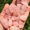May include: A collection of tumbled rose quartz stones in various sizes and shapes. The stones are a pale pink color and have a smooth, polished finish.