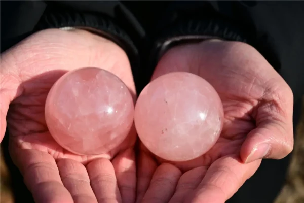 May include: Two polished rose quartz spheres with a translucent, pale pink appearance. Each stone features a smooth, rounded surface with natural internal incl May include: Two polished rose quartz spheres with a translucent, pale pink appearance. Each stone features a smooth, rounded surface with natural internal inclusions and subtle variations in color, reflecting light across their curved forms.